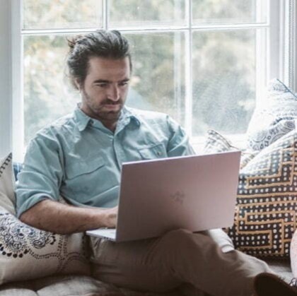 Man looking at laptop while sitting on sofa