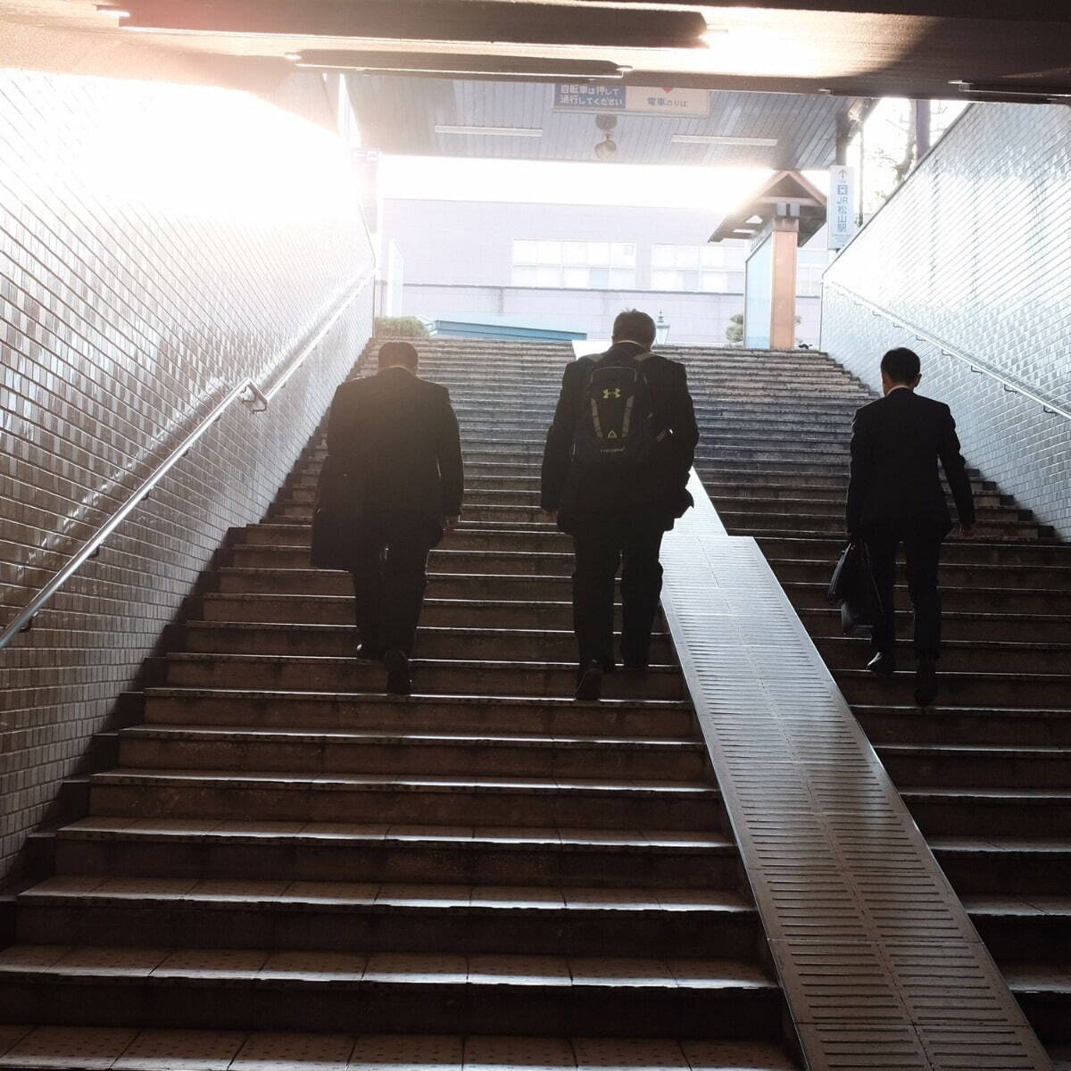 People walking upstairs towards sunlight